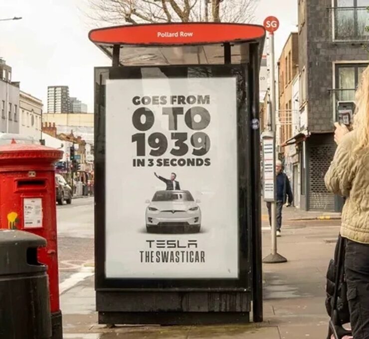 an ad on a bus stop in london advertises tesla vehicles as swasticars