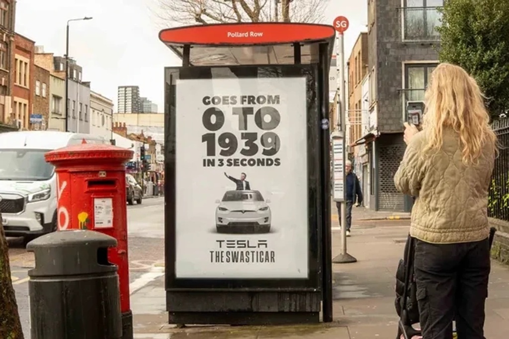 an ad on a bus stop in london advertises tesla vehicles as swasticars